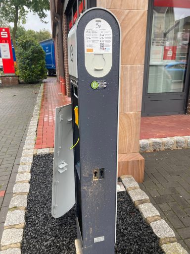 Parkscheinautomat an einer Straße, mit geöffnetem Fach und sichtbaren Bedienelementen.